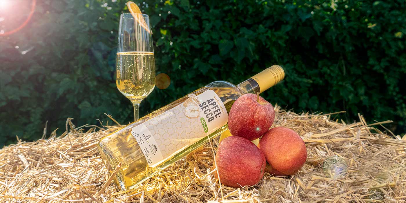 Eine Flasche des Saarland inklusive-Apfelsecco auf einem Strohballen