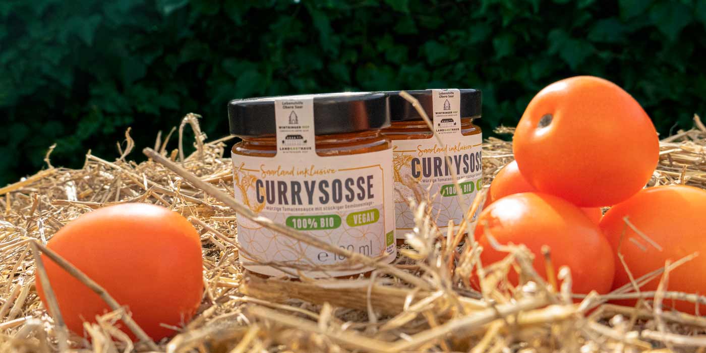 Zwei Gläser der Saarland inklusive-Currysoße auf einem Strohballen