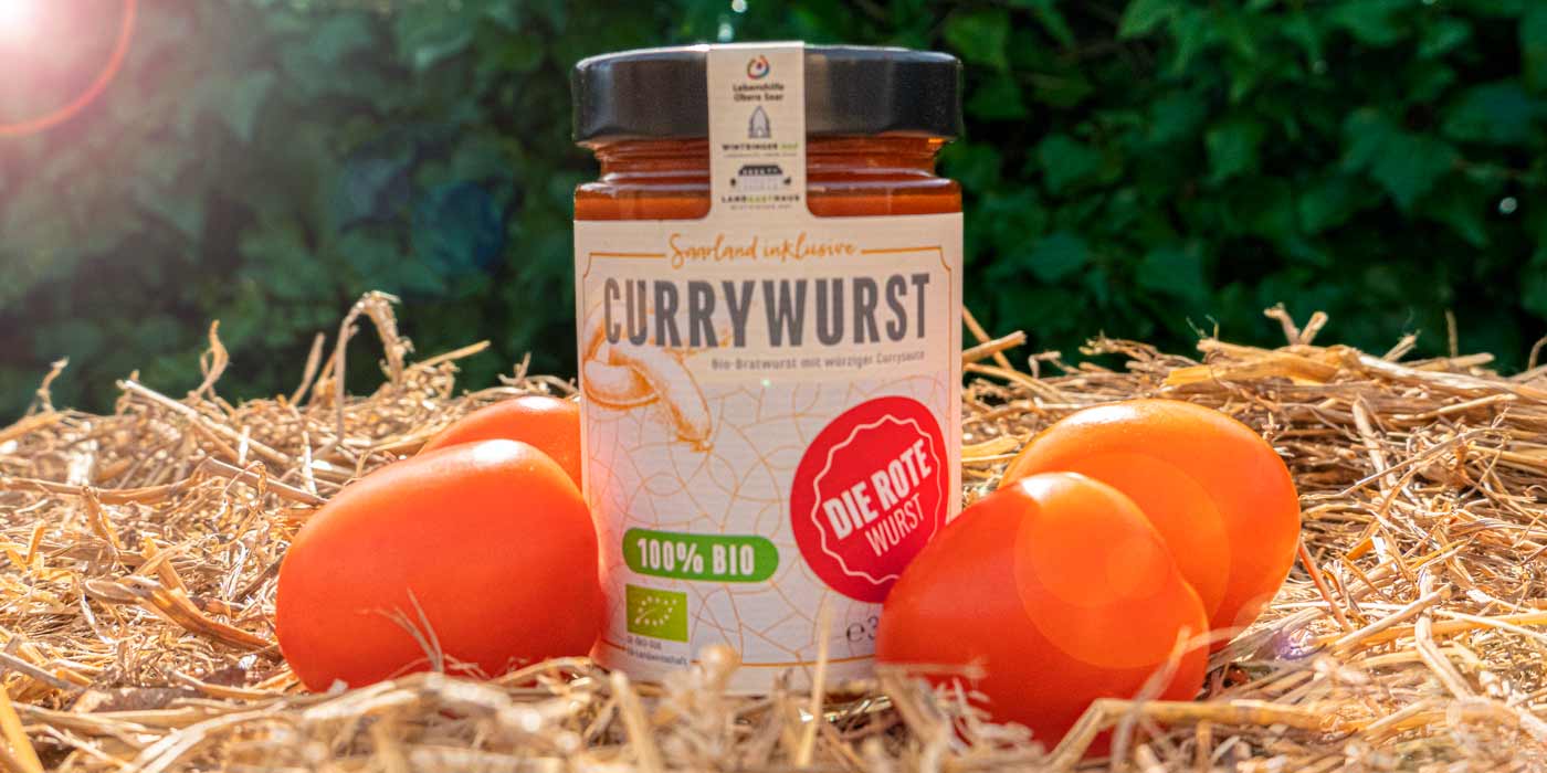 Ein Glas der roten Saarland inklusive-Currywurst auf einem Strohballen