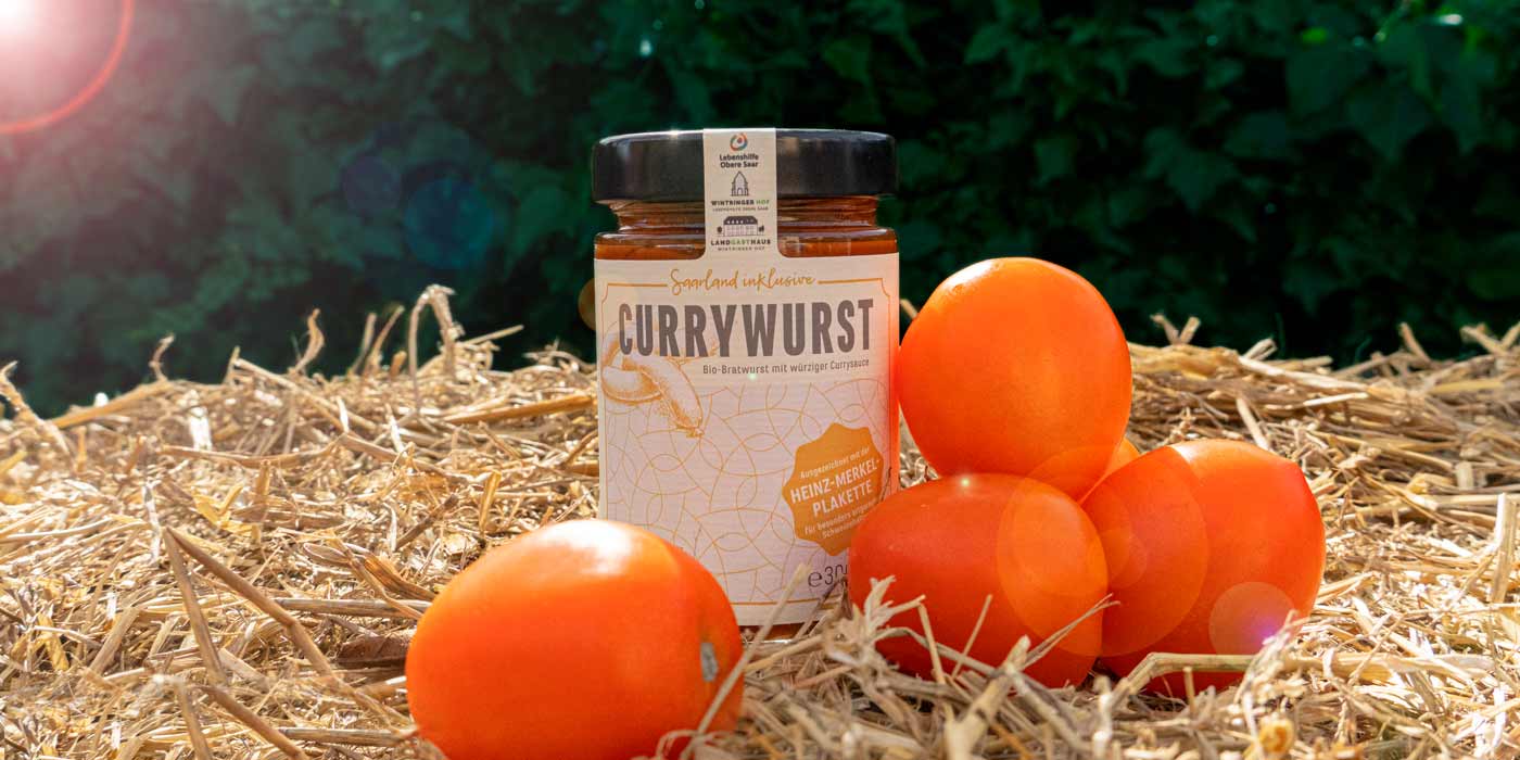 Ein Glas der Saarland inklusive-Currywurst auf einem Strohballen