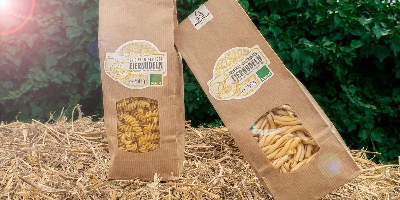 Zwei Packungen der Saarland inklusive-Eiernudeln auf einem Strohballen