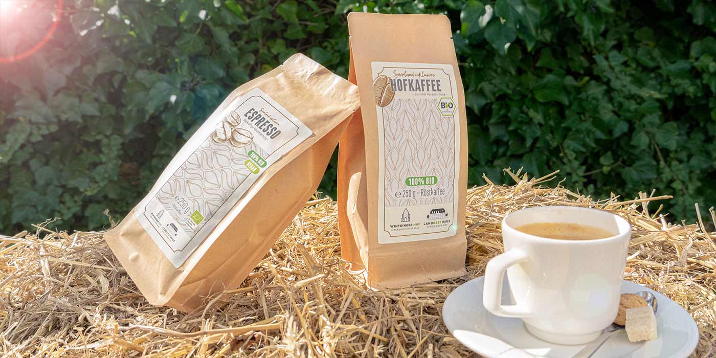 Jeweils eine Packungder des Saarland inklusive-Hofkaffees und des Hofespressos auf einem Strohballen