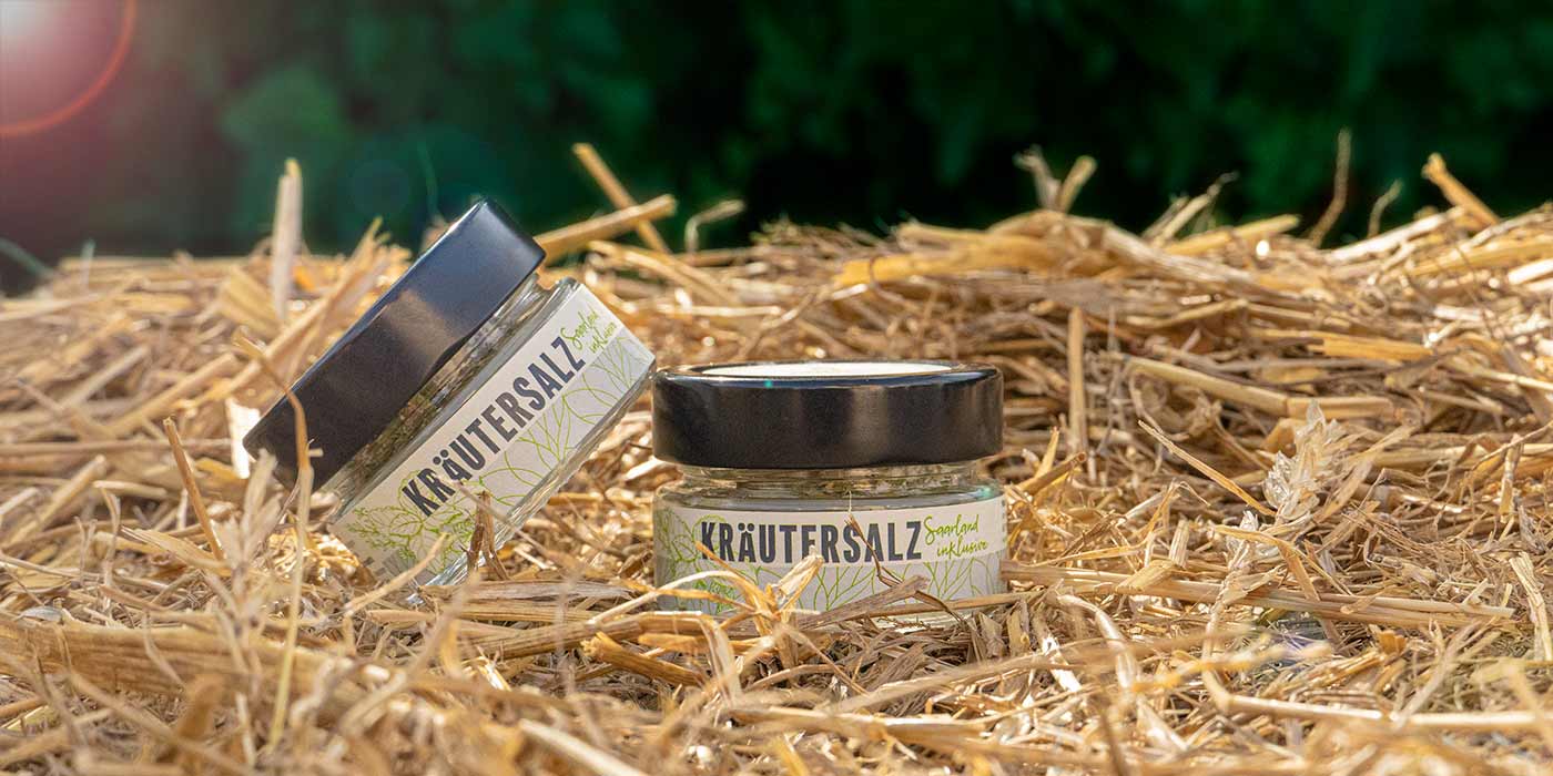 Zwei Gläser des Saarland inklusive-Kräutersalz auf einem Strohballen