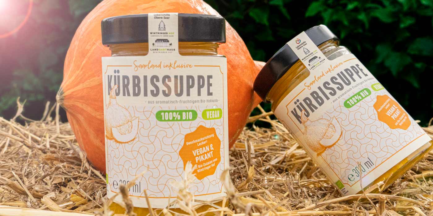 Zwei Gläser der Saarland inklusive-Kürbissuppe auf einem Strohballen