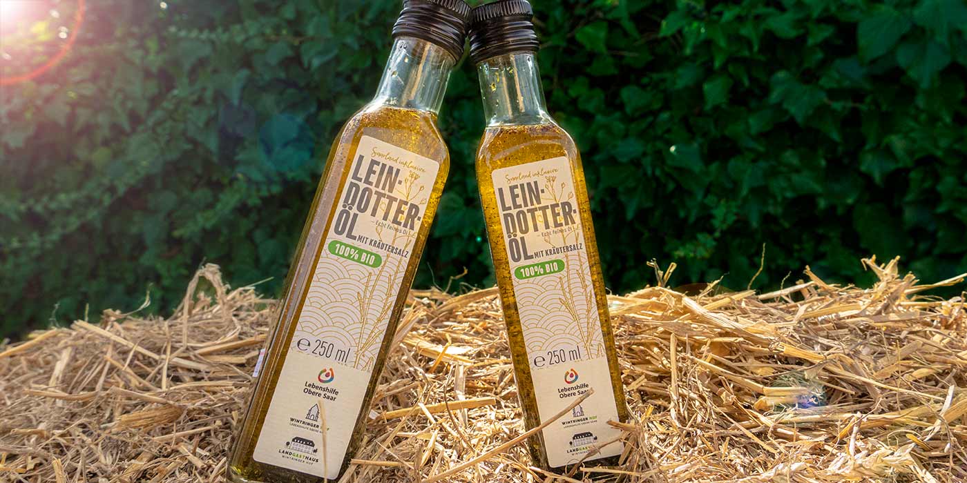 Zwei Flaschen des Saarland inklusive-Leindotteröls auf einem Strohballen