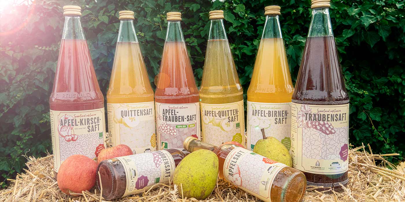 Jeweils eine Flasche der Saarland inklusive-Säfte auf einem Strohballen