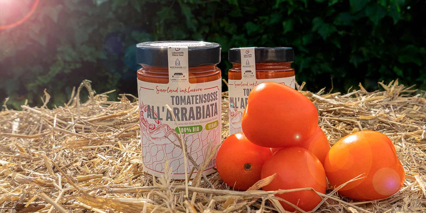 Zwei Gläser der Saarland inklusive-Tomatensoße all arrabiata auf einem Strohballen