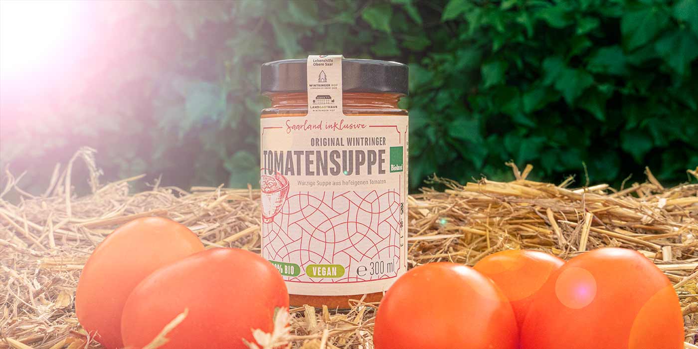 Ein Glas der Saarland inklusive-Tomatensuppe auf einem Strohballen